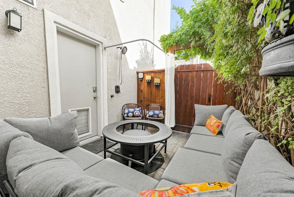 Brownstone Patio: A private side yard nook accessed right from the garage. Unwind on the cozy sectional, rinse off under the starlit outdoor shower, or enjoy a drink from the mini-fridge by the warm smokeless firepit. 